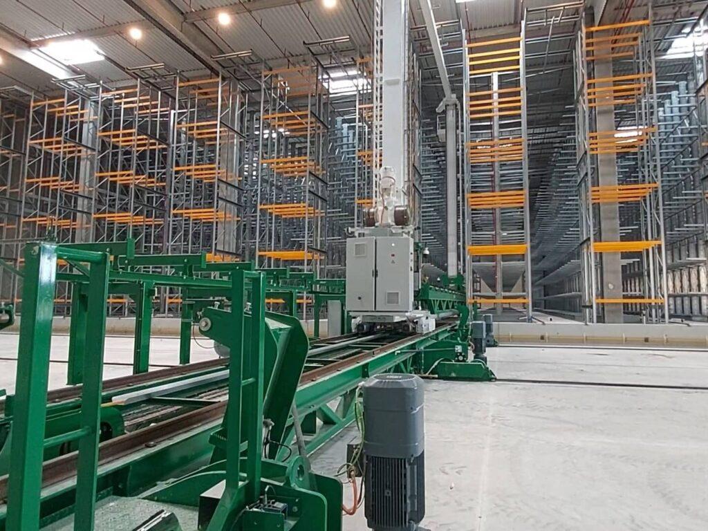 Transstockeur et convoyeurs devant des rayonnages de stockage